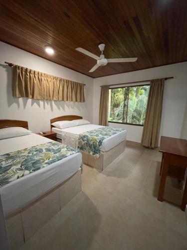 um quarto com 2 camas e uma ventoinha de tecto em Apartotel Flamboyant em Jacó