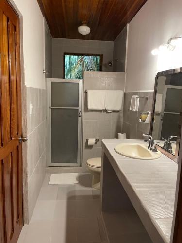a bathroom with a sink and a toilet and a mirror at Apartotel Flamboyant in Jacó