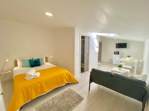 a bedroom with a large bed with a yellow blanket at BrightHouse Nazaré - Modern Apartments in Nazaré