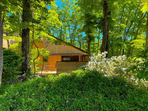 a house in the woods with trees and flowers at Asagiri Chalet Hakuba in Hakuba