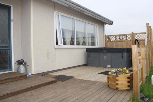 a house with a wooden deck with a window at Stóri-Bakki Guesthouse-with hot tub in Egilsstadir