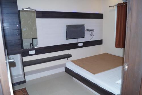 a small room with a bed and a tv at Shree Akshar Restaurant and Hotel in Ahmedabad