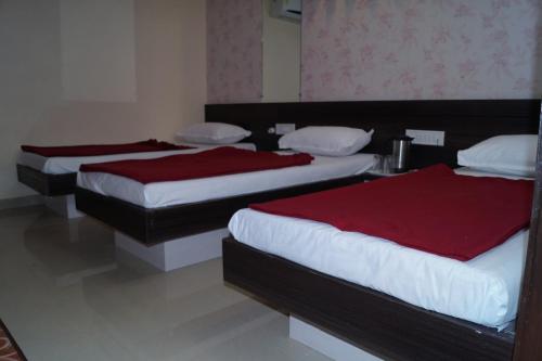 two beds in a hotel room with red sheets at Shree Akshar Restaurant and Hotel in Ahmedabad