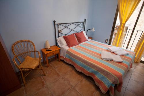 a bedroom with a bed and a chair and a window at Apartamentos Maribel in Calaceite