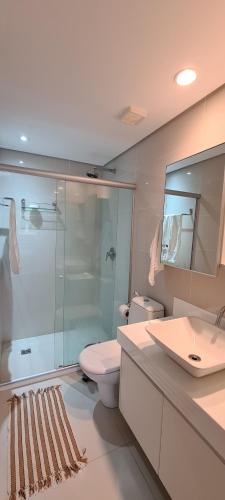 a bathroom with a toilet and a glass shower at Malawi Muro Alto - Flat 103H Térreo in Porto De Galinhas