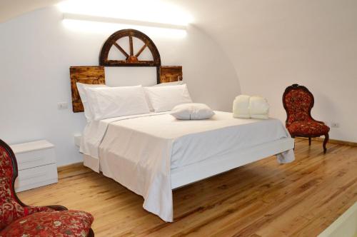 a bedroom with a bed with white sheets and two chairs at Palazzo Grandori Alloggi Turistici in Viterbo