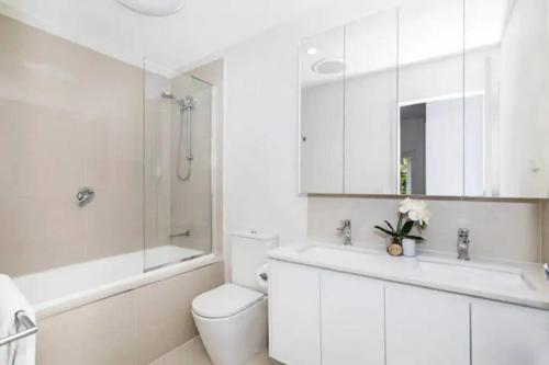 a white bathroom with a toilet and a sink at Park Avenue Terrace 1BR, 4km to CBD, WiFi, Park in Brisbane