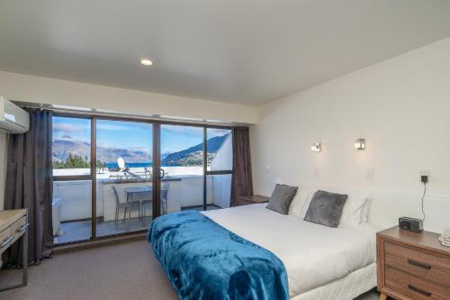 a bedroom with a bed and a balcony with a desk at Melbourne Lodge Queenstown in Queenstown