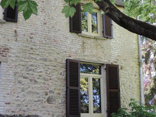 an old stone building with black shuttered windows at B&B Le Valangré in Chaumont-Gistoux