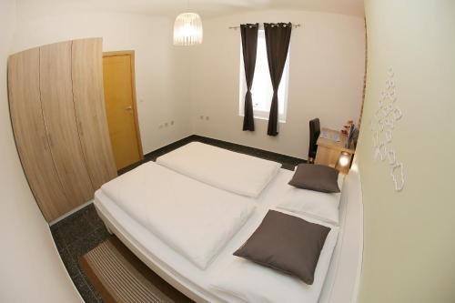 een kleine slaapkamer met een wit bed met bruine kussens bij Zadar Street Apartments and Room in Zadar