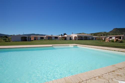 a large swimming pool in front of a house at Tenute Costadoria (Valle di Cynara) in Valledoria