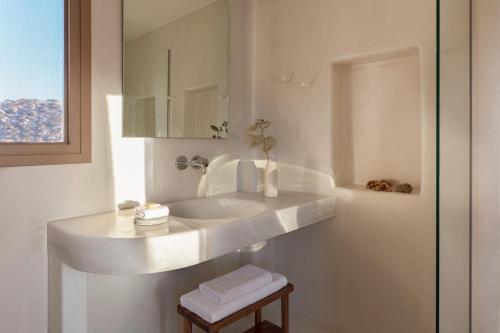 a white bathroom with a sink and a mirror at Ammothines Cycladic Suites in Naxos Chora
