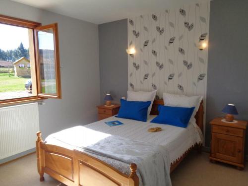 a bedroom with a bed with blue pillows and a window at Gîte La Tuilière, 4 pièces, 6 personnes - FR-1-496-93 in Saint-Priest-la-Prugne