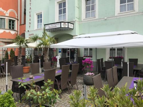 un patio extérieur avec des tables, des chaises et des parasols dans l'établissement Hotel-Restaurant zum Donaueck Mauthausen, à Mauthausen