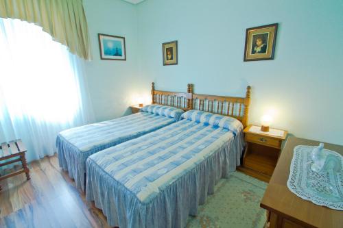 a bedroom with a bed with a blue comforter at Hospedaje Roiz in Suances