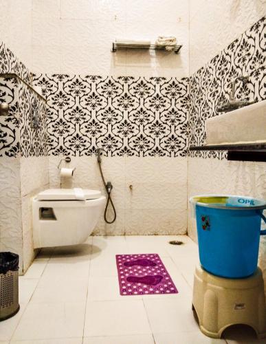 a bathroom with a toilet and a pink rug at Dwivedi Hotels Sri Omkar Palace in Varanasi
