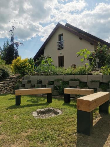 two benches sitting in the grass in front of a house at U Tří pecek - Malenice in Malenitz