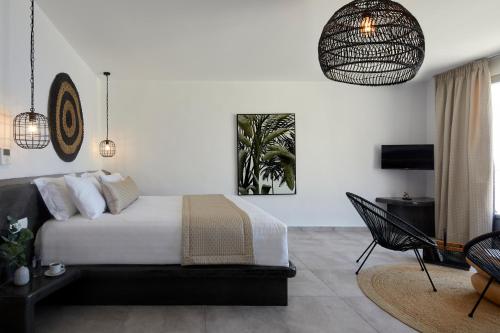 a bedroom with a bed and a table and a chair at Thermes Luxury Villas And Spa in Megalokhori