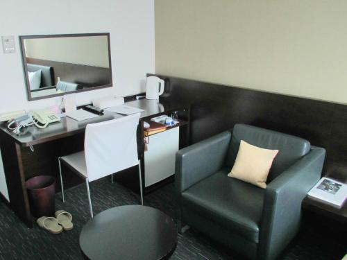 a room with a chair and a desk with a mirror at Muroran Prince Hotel in Muroran