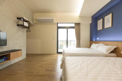 a hotel room with two beds and a tv at 探尋旅者Homestay in Magong