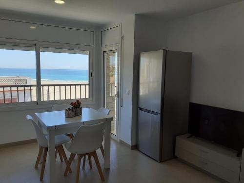 eine Küche mit einem Kühlschrank sowie einem Tisch und Stühlen in der Unterkunft Apartamentos Dins Mar Apto. 8 in Torredembarra