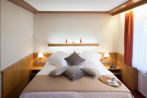 a large bed with pillows and a tray on it at Hotel Drei Morgen in Leinfelden-Echterdingen