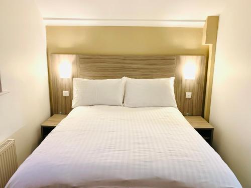 a large bed with white sheets and pillows at De Regency Style Hotel in Redditch