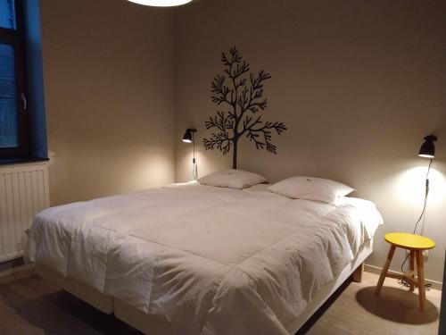 a bedroom with a white bed with a tree on the wall at Ardennature vakantiehuizen met privé-sauna in La Roche-en-Ardenne