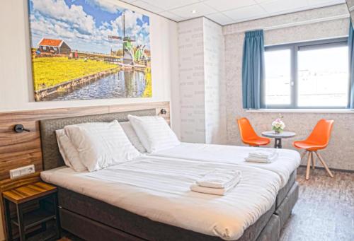 a bedroom with a bed with a painting on the wall at Harbour Hotel IJmuiden in IJmuiden