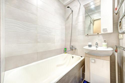 ein Badezimmer mit einer Badewanne und einem Waschbecken in der Unterkunft Apartments near Ocean Plaza Druzhby Narodov Boulevard 8a in Kiew