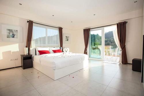 a bedroom with a white bed and a large window at Blue Cove Pool Villa in Trat
