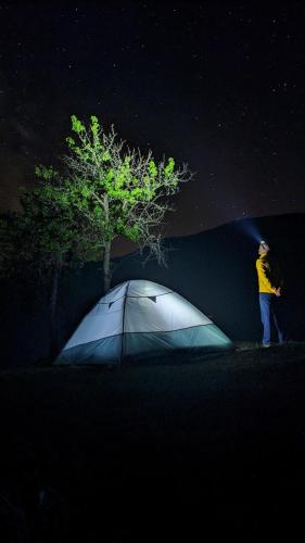 a man standing next to a tent under a tree at Kljajevica Orchard in Pljevlja
