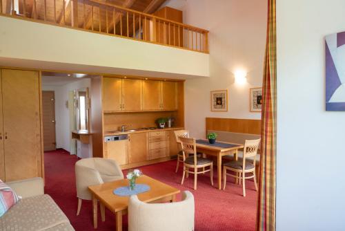 Aparthotel Schindlhaus/Alpin في سول: مطبخ وغرفة معيشة مع طاولة وكراسي
