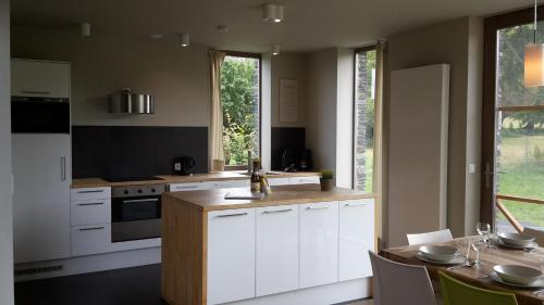 a kitchen with white cabinets and a table with chairs at Ardennature vakantiehuizen met privé-sauna in La Roche-en-Ardenne