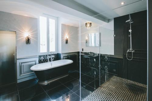 Paraza的住宿－帕拉扎城堡酒店，黑色浴室设有浴缸和淋浴。