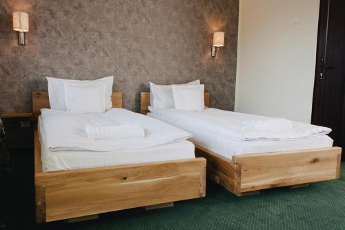2 camas en una habitación con sábanas y almohadas blancas en Pensiune Restaurant Flamingo, en Sighetu Marmaţiei