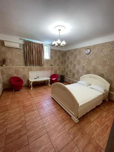 a bedroom with a bed and two red chairs at Inn Kavkaz in Makhachkala