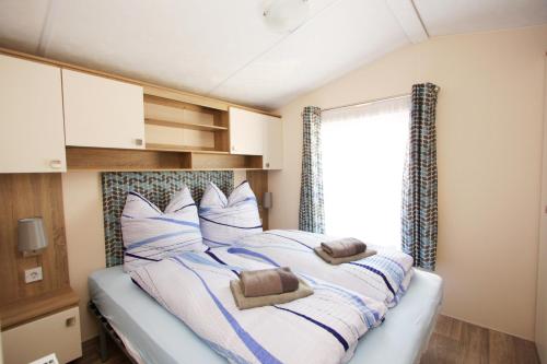 een slaapkamer met een bed met kussens en een raam bij schönes Chalet Tinyhouse in Ostseenähe 13km - sehr ruhige Dorflage in Vogtshagen
