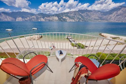 a balcony with red chairs and a view of the beach at Hotel Europa in Malcesine