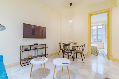 a living room with a table and chairs and a tv at Mosaiko Homes Catedral Granada in Granada