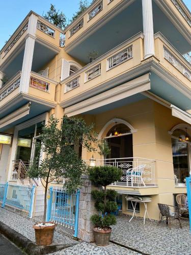 a yellow building with a balcony and tables on it at Royal's Studios in Loutra Edipsou