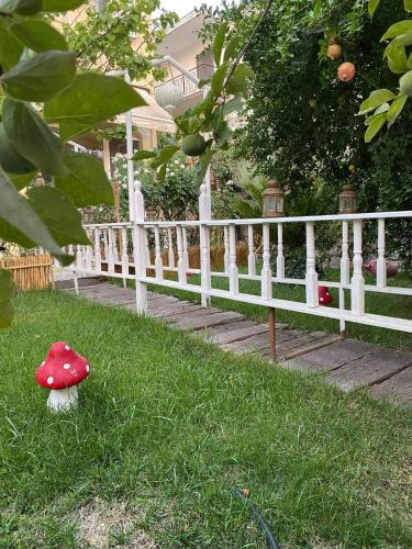 a red mushroom sitting on the grass next to a white fence at Royal's Studios in Loutra Edipsou