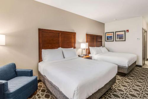 a hotel room with two beds and a blue couch at Comfort Inn & Suites Brevard North in Brevard