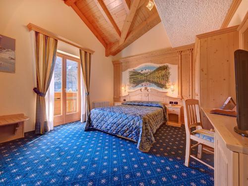 ein Schlafzimmer mit einem Bett und einem blauen Teppich in der Unterkunft Hotel Madonna delle Nevi in Folgarida