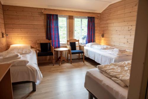 a room with three beds and a table and chairs at Raubergstulen fjellstue og hytter in Boverdalen
