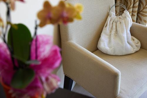 a white purse sitting on a chair next to flowers at Hotel Europa in Malcesine