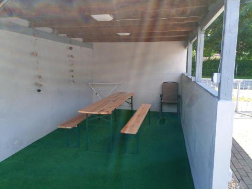 a picnic table and bench in a room with green carpet at kleines gemütliches Ferienhaus in Poseritz