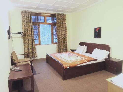 a bedroom with a bed and a table and a window at Troutland Hotel Naran in Naran