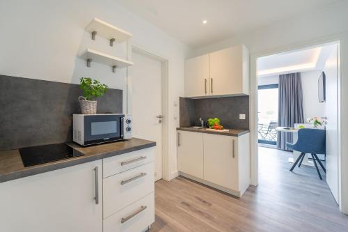 a kitchen with white cabinets and a table with a microwave at Marina Martinshafen in Sassnitz