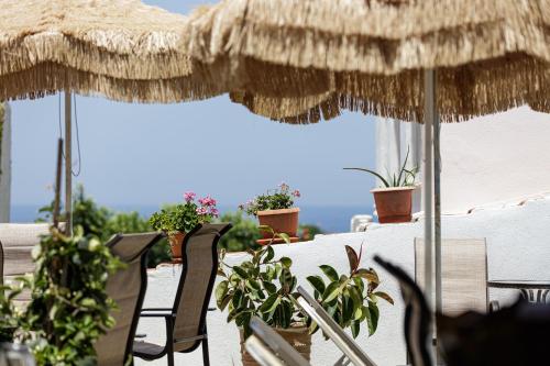a table with chairs and an umbrella and potted plants at Kasteli Studios & Apartments in Panormos Rethymno